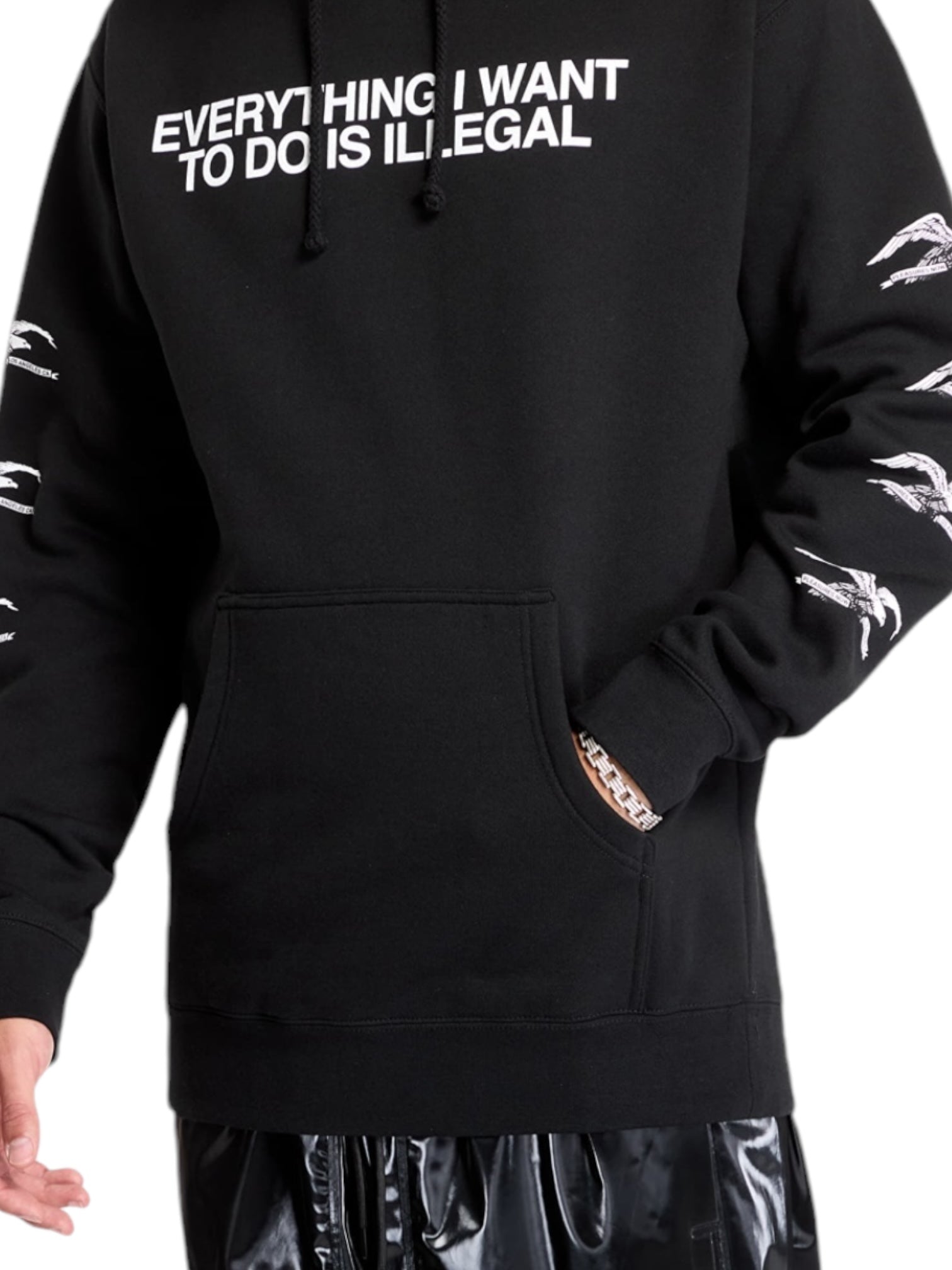 A person wearing the Pleasures Illegal Hoodie Black by PLEASURES, featuring soft cotton material and patterned sleeves with the text "EVERYTHING I WANT TO DO IS ILLEGAL," paired with shiny black polyester pants.
