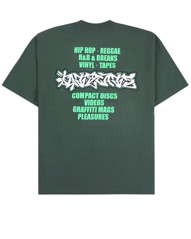 The Pleasures Melrose T-shirt Ivy by PLEASURES is a dark green 100% cotton tee featuring graffiti-style text with music genres, formats, and Fat Beats magazines in green and white on the back.