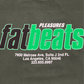 The Pleasures Melrose T-shirt Ivy by PLEASURES is a dark, 100% cotton tee featuring "PLEASURES Fat Beats" and the Melrose Ave address printed on the front. Made in the USA.