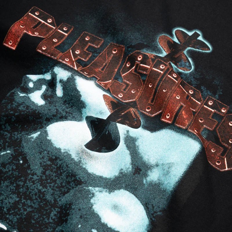 Close-up of the Pleasures Migraine T-shirt Black Edge by PLEASURES, a cotton tee featuring metallic, riveted "PLEASURES" lettering over a blue and white abstract print, designed with a boxy fit for a relaxed look.