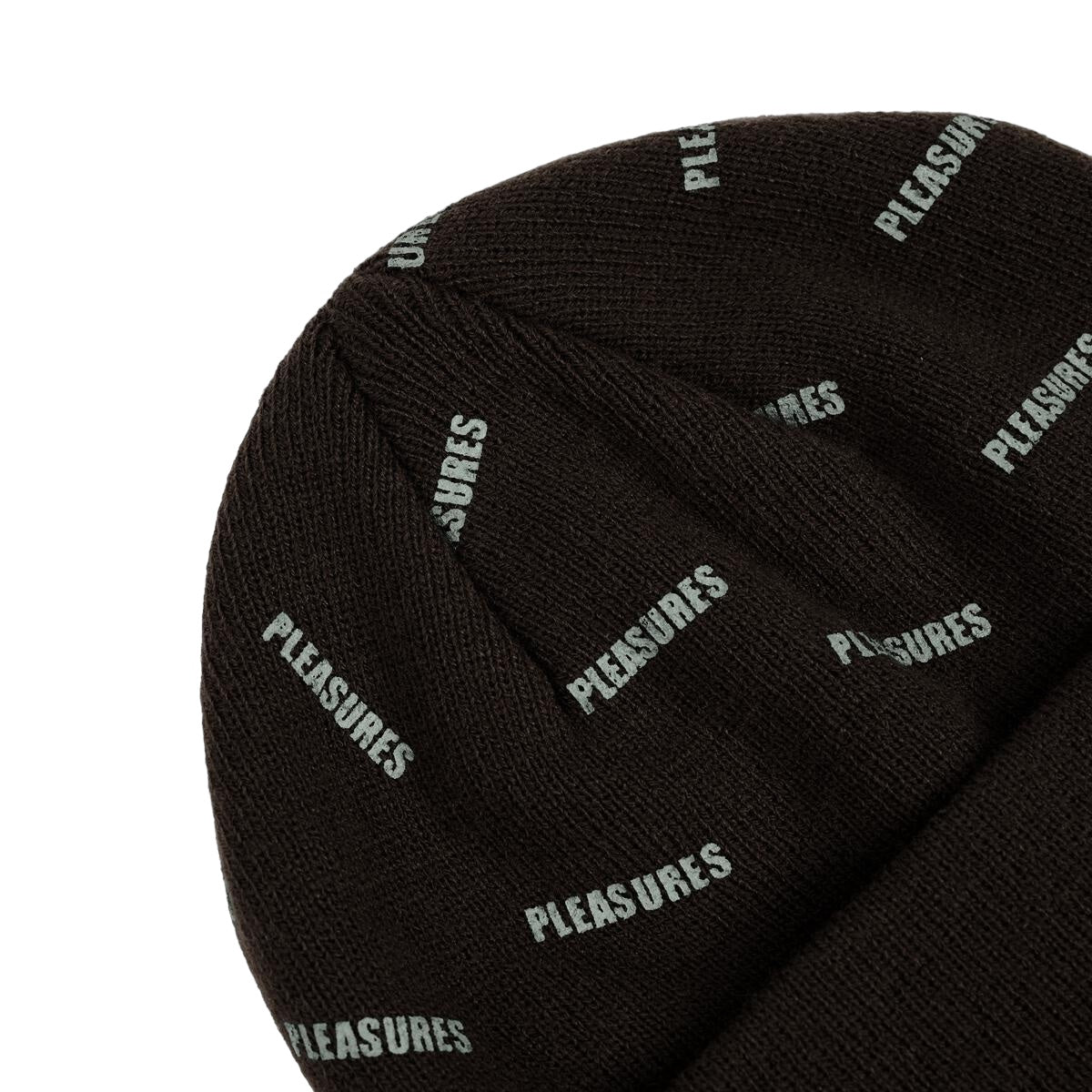 A close-up of the PLEASURES SPRINKLE BEANIE BLACK, featuring white "PLEASURES" text repeatedly printed on the dark knitted fabric.