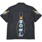 The PLEASURES Time Bowling Button Up Black is a short-sleeve polyester shirt featuring neon-style “BOWL” and pin graphics on the back, plus playful bowling pin designs on both sleeves.