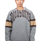 Someone sports the "Pleasures Twitch Chunky Knit Sweat Grey," featuring wool blend and "PLEASURES" embroidery on the front, with chic brown and beige sleeve bands.