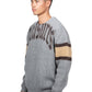 Someone is wearing the Pleasures Twitch Chunky Knit Sweat Grey by PLEASURES, featuring brown and yellow striped sleeves, against a white backdrop.