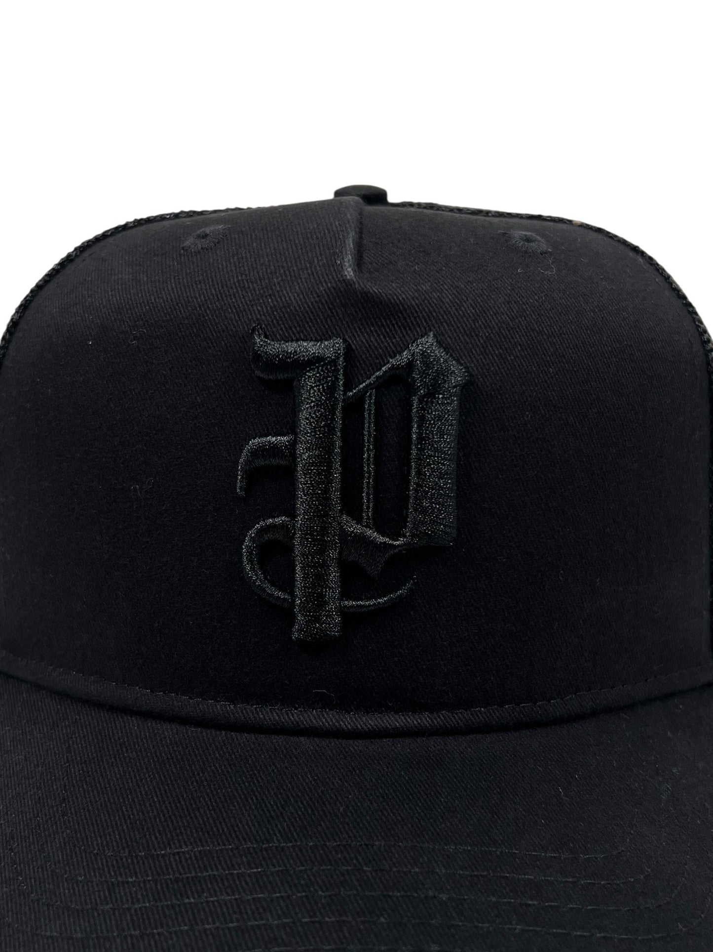 The PURPLE BRAND A2054-TTGT224 Cotton Twill Trucker Hat in black features a raised, embroidered gothic "P" on the front panel, inspired by bold Purple Brand style.