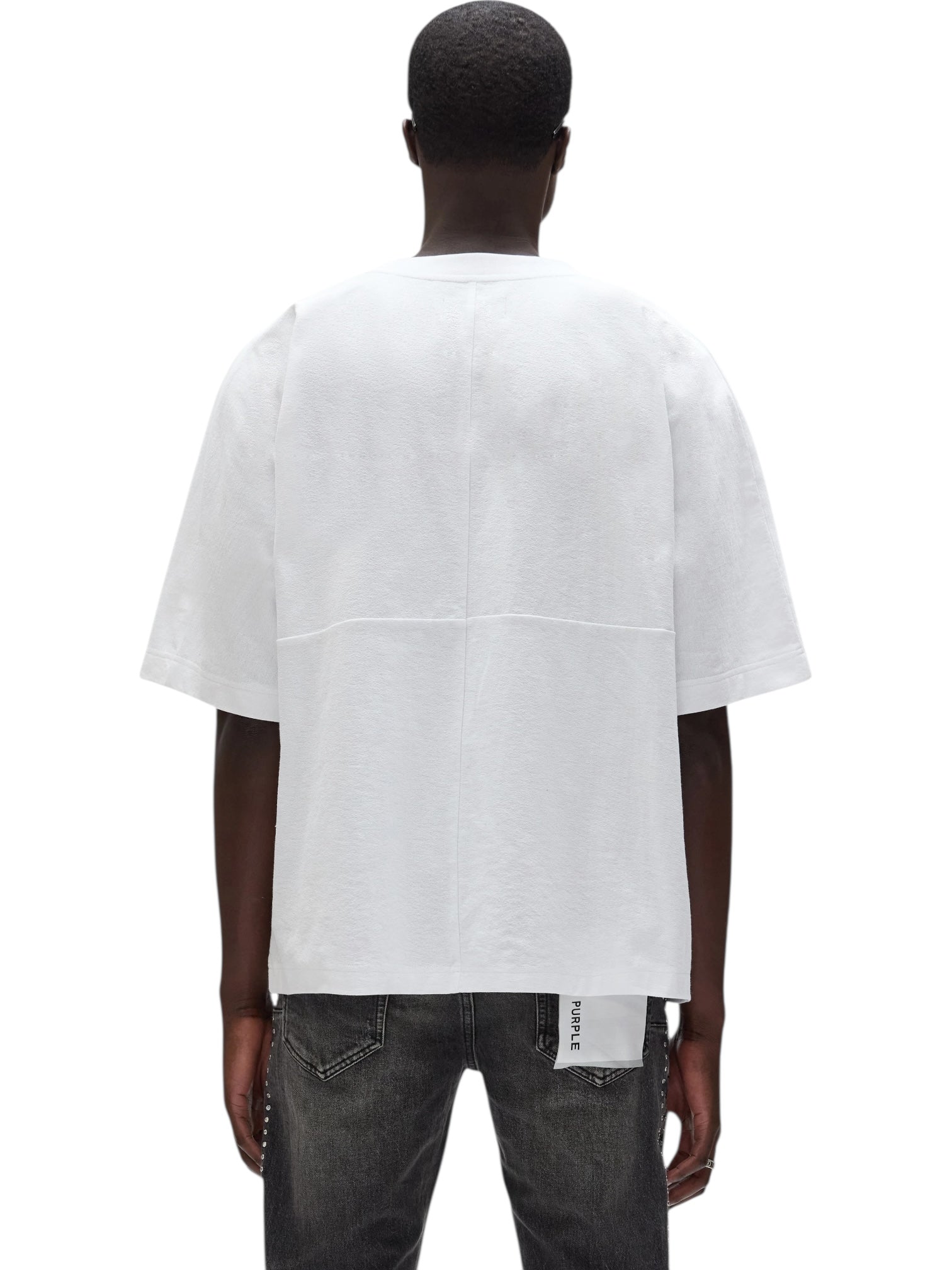 A person wearing a PURPLE BRAND M1057-TWFM325 Textured Jersey Top in white and dark jeans, shown from the back against a plain background.