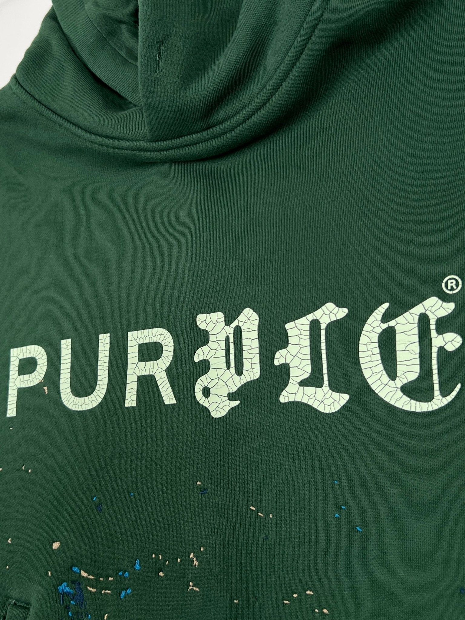 The Purple Brand M4104-HFGH425 Heavyweight Fleece Hoodie in green features "PURPLE" in large, cracked white Gothic letters across the chest with a vintage crackle print.