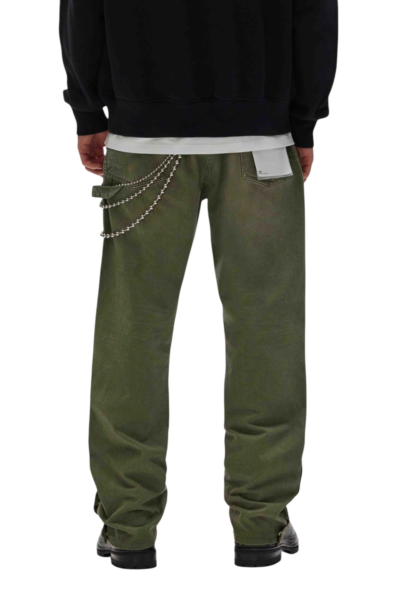 Seen from the back, a person is wearing PURPLE BRAND's M5005-CTMI Snap Carpenter Pant Green with a side chain accessory, paired with stylish black shoes and a dark sweatshirt for an effortlessly chic look.