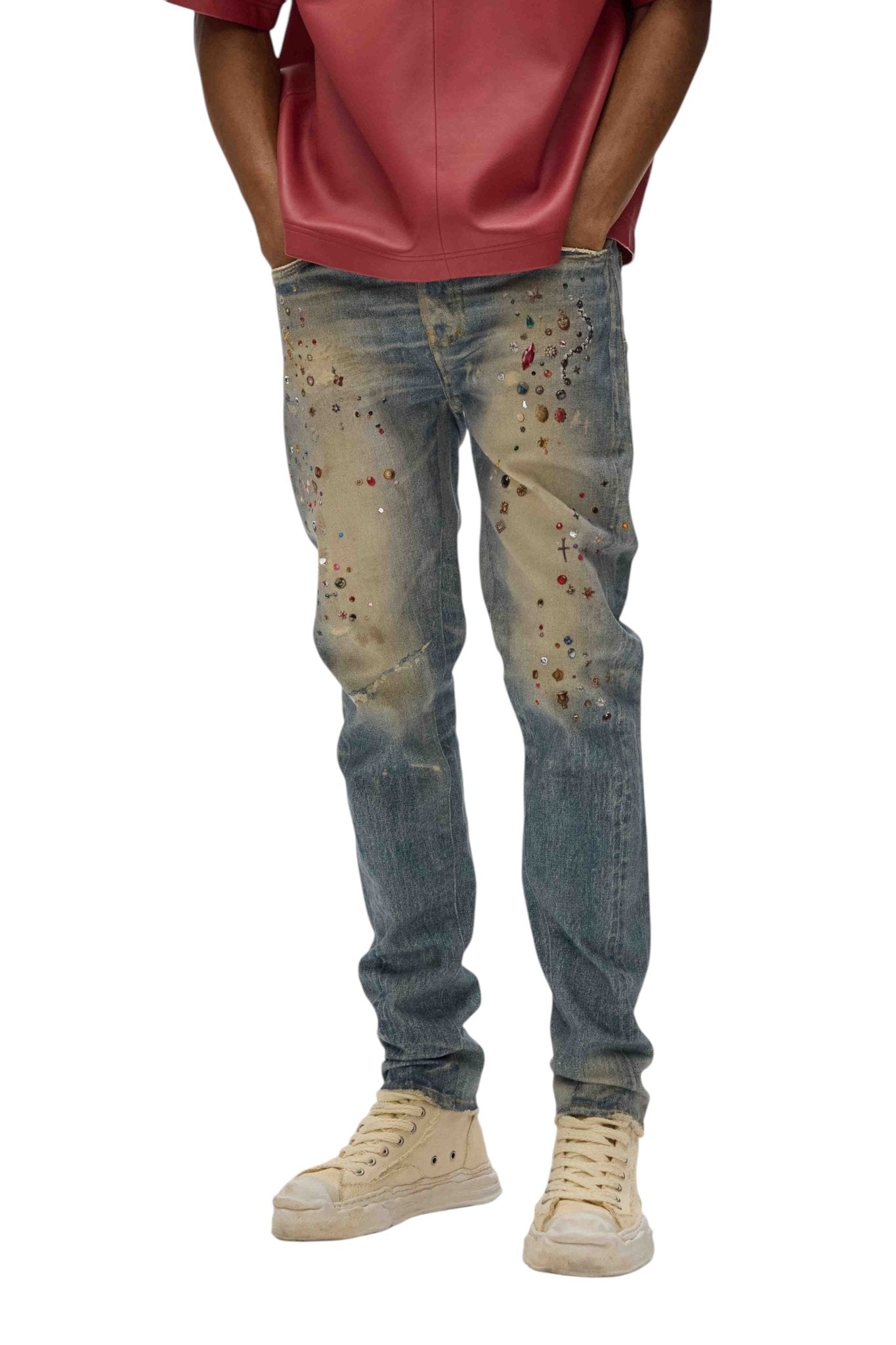 Person in Purple Brand P001-CYWI distressed skinny jeans with paint splatters, beige high-top sneakers, and a red shirt.