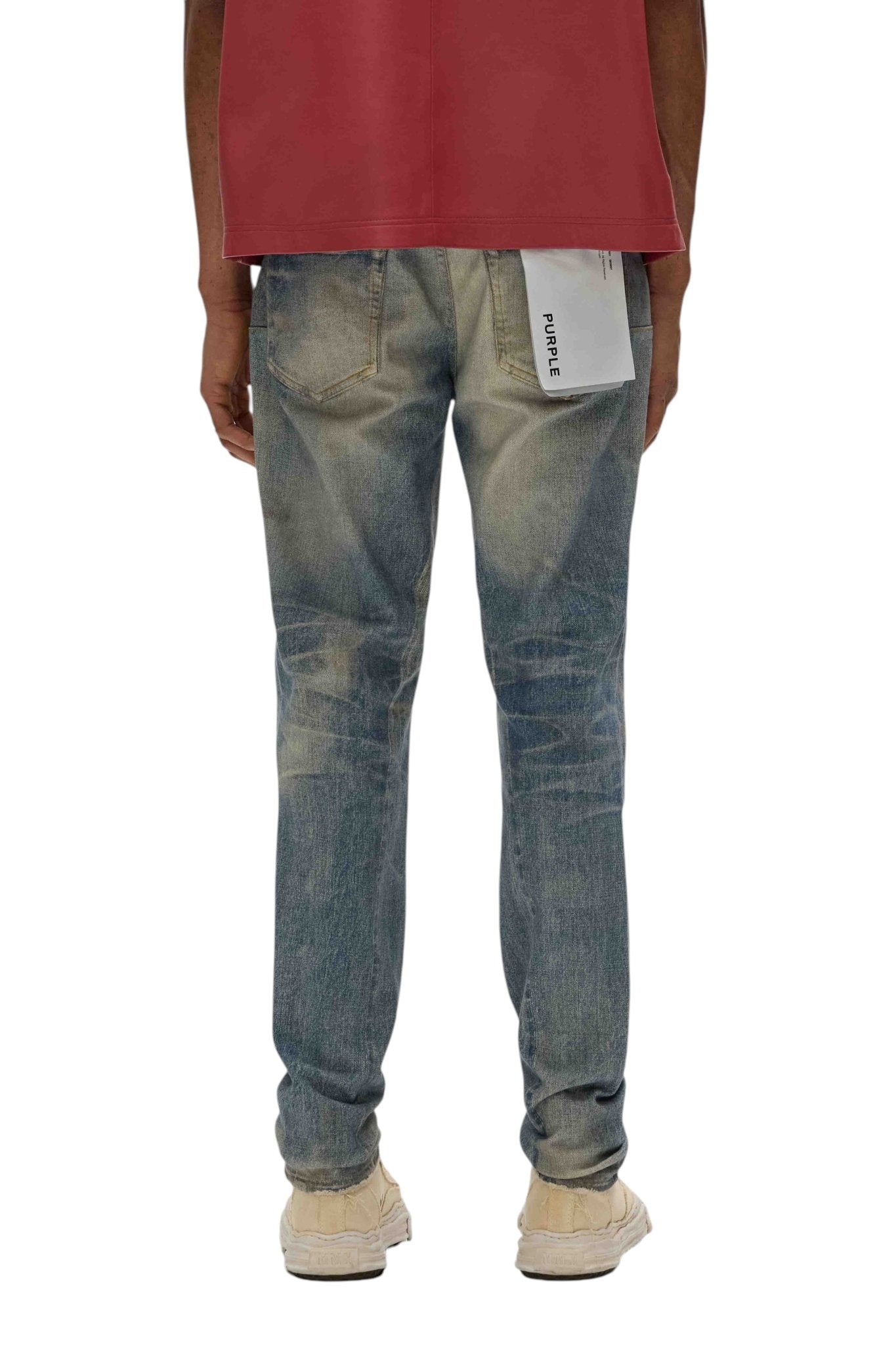 A person in the Purple Brand P001-CYWI Skinny Cyanine Jewel Indigo is seen from behind, wearing a red shirt. The premium stretch denim contours beautifully with a white label tucked into the back right pocket.