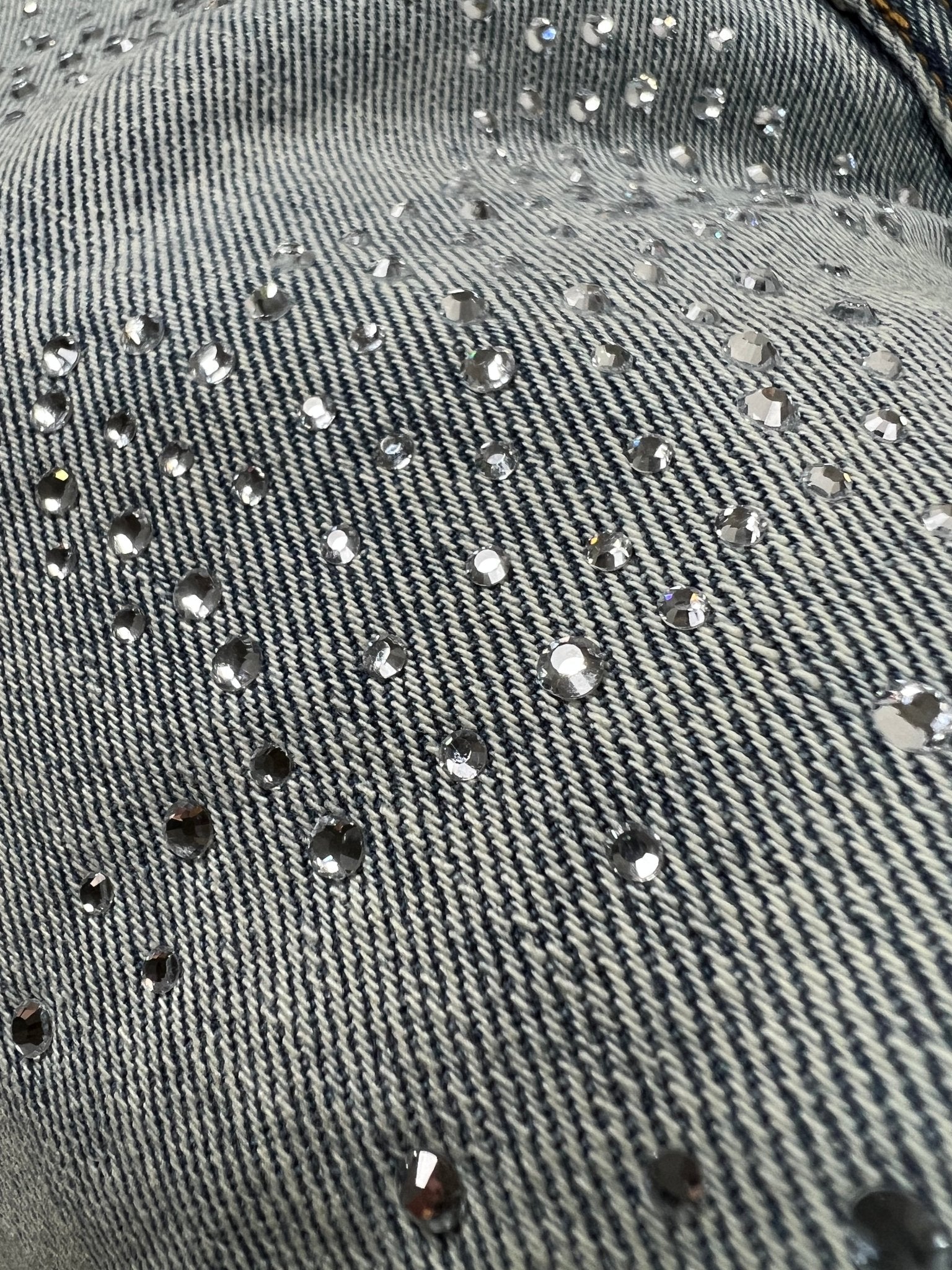 Close-up of light blue premium stretch denim adorned with scattered small, round rhinestones—perfect for elevating your PURPLE BRAND P001-SALT425 Skinny Atlin Blitz Indigo jeans collection.