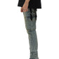 A person in a black shirt and PURPLE BRAND's P001-SCPL Skinny Cargo Pumice Lt Indigo jeans with patchwork stands sideways. Black pointed-toe boots complete the look, while a black bandana hangs casually from a back pocket.