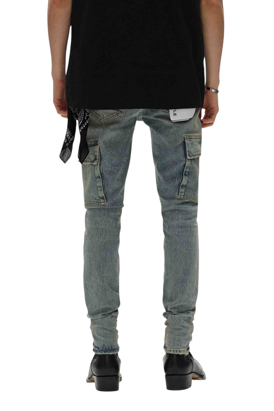 A person is seen from the back wearing a black shirt and the Purple Brand P001-SCPL Skinny Cargo Pumice Lt Indigo jeans with side pockets. They sport black shoes, and a bandana hangs from the premium stretch denim pocket, adding a touch of style to their look.