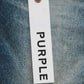 A white tag labeled "PURPLE BRAND" hangs against the blue premium stretch denim, capturing the allure of the chic Purple Brand P001-SNFD Skinny 9 To 5 DK Indigo low rise skinny jeans.