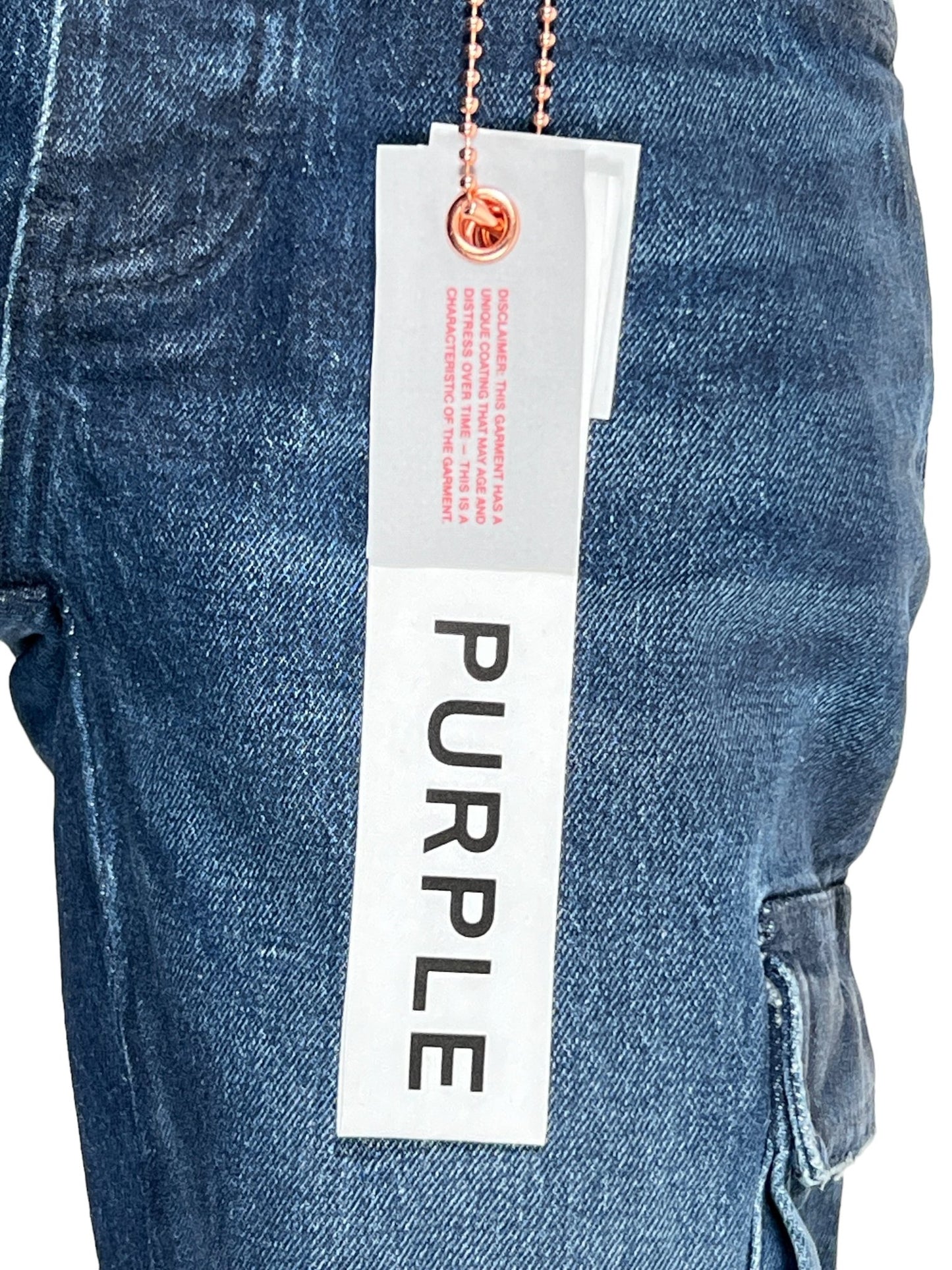 A close-up of the PURPLE BRAND P004-CFGS Cargo Flare Vintage Coated Dark Indigo jeans with a white tag labeled "PURPLE" attached to the waistband.