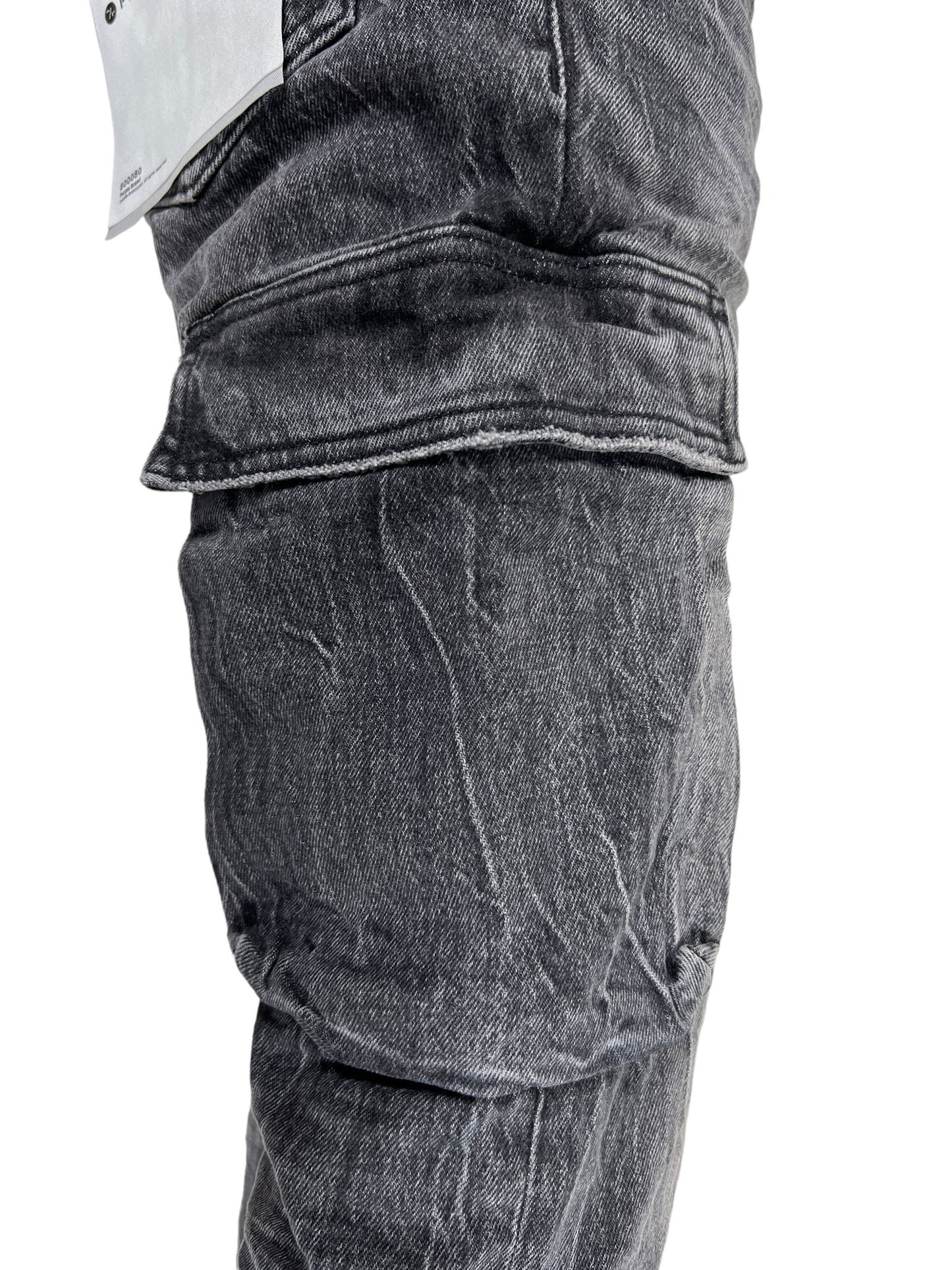 Close-up of a pair of PURPLE BRAND P004-CFTW CARGO FLARE TINTED WORN BLACK denim jeans worn by a person, focusing on the knee area. The fabric appears slightly creased, resembling the vintage charm of tinted worn jeans.