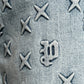 Close-up of indigo denim with embossed X shapes and Gothic "w" details, as seen on the PURPLE BRAND P004-FOBL425 Flare Mono Embossed Indigo jeans.