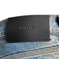 Close-up of Purple Brand P004-GBMF Gaia Blowout Flare Indigo Denim jeans with a black leather "PURPLE BRAND" patch on the waistband, showcasing the sophisticated style for Spring/Summer 2025.