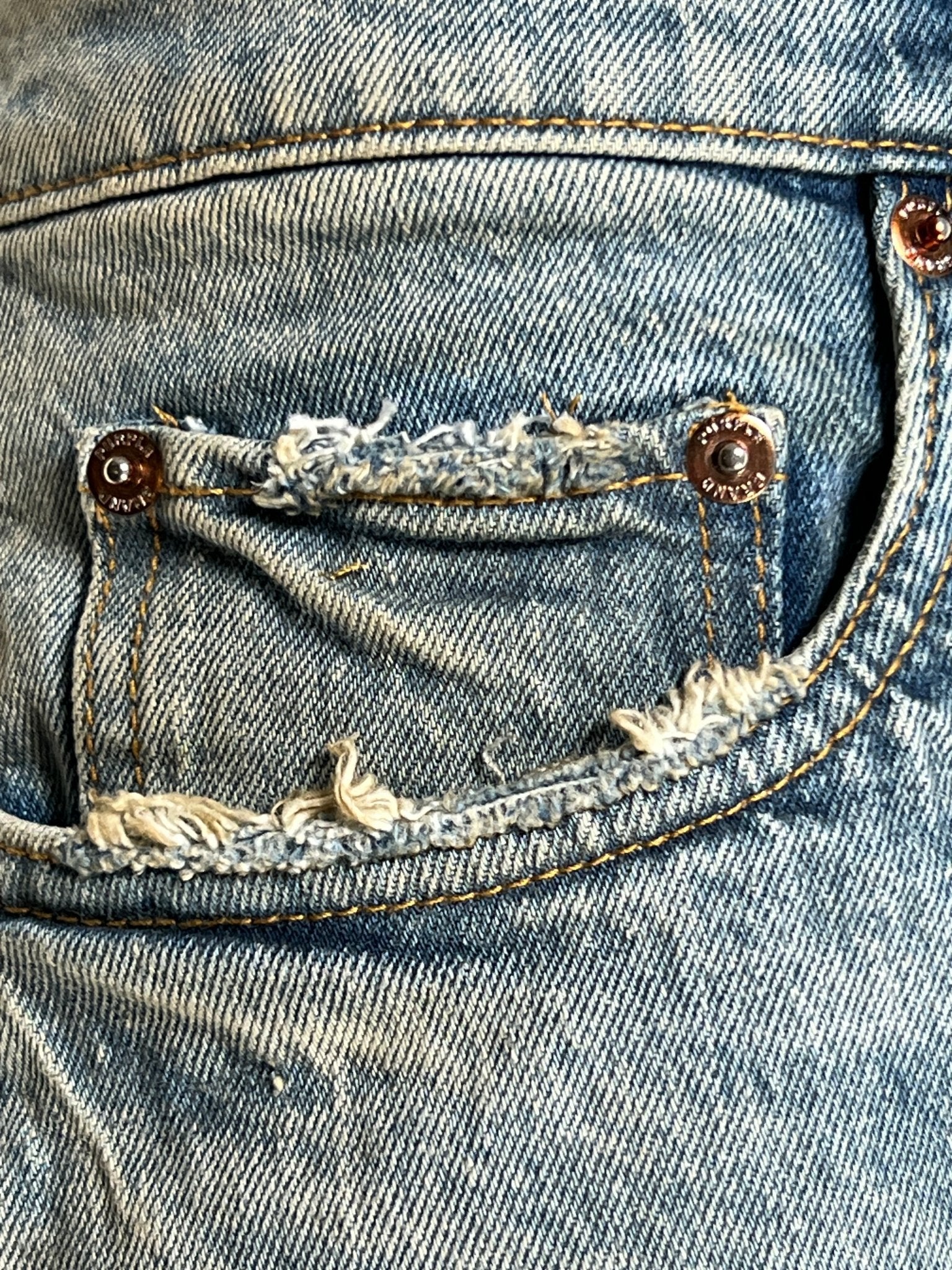Zoom in on the detailed Indigo denim pocket from the PURPLE BRAND P004-GBMF Gaia Blowout Flare, featuring frayed edges and orange stitching for Spring/Summer 2025.
