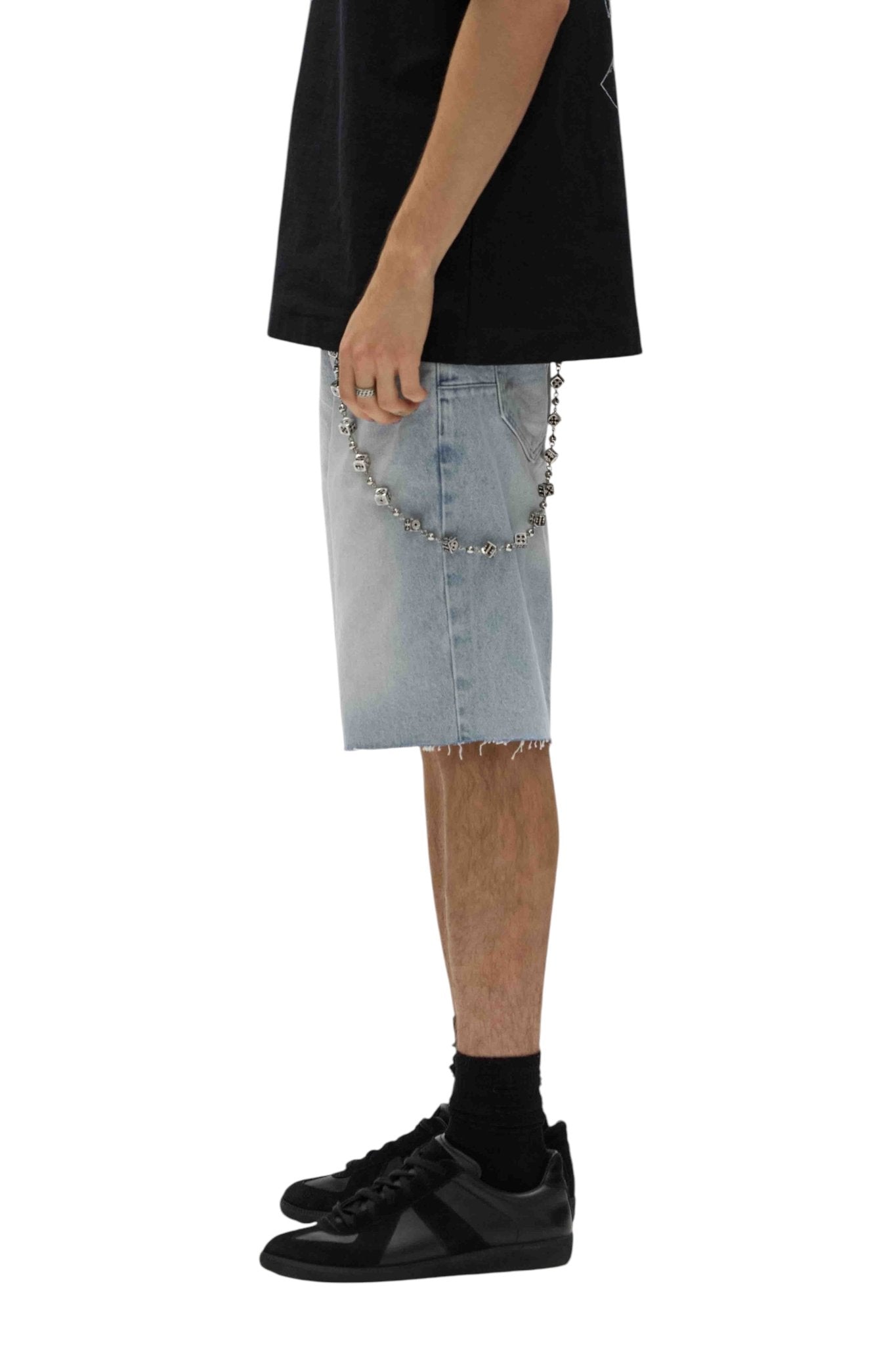 A person wears a black shirt and Purple Brand P059-CBLT Ciel Blue Shorts, featuring a chain accessory for a relaxed fit. Paired with black socks and sneakers, they stand against a white background, showcasing a vintage style.