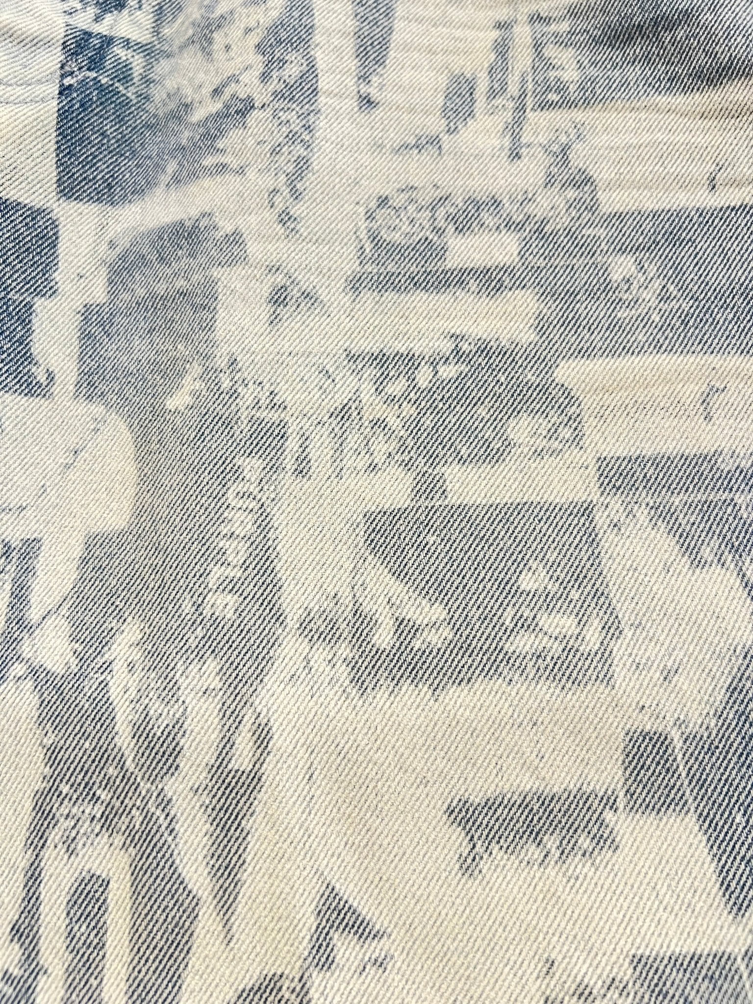 Close-up of PURPLE BRAND P059-GRPS325-Grunge Print Shorts Indigo shows blue and white premium cotton denim with a faded, vintage-style image of people and market stalls for a textured effect.