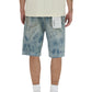A person is shown from the back wearing a textured white shirt and PURPLE BRAND P059-MXPS Mixed Paint Shorts Indigo, featuring light blue denim, relaxed fit, frayed hems, and a white tag on the pocket. White socks and sneakers complete the look.