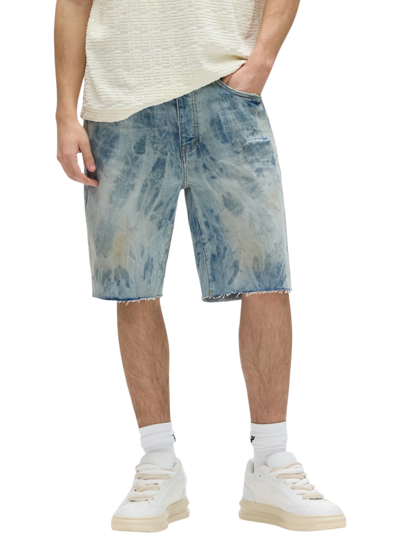 A person wearing PURPLE BRAND Purple Brand P059-MXPS Mixed Paint Shorts Indigo, white socks, cream sneakers, and a cream textured shirt. Only the lower body is visible.