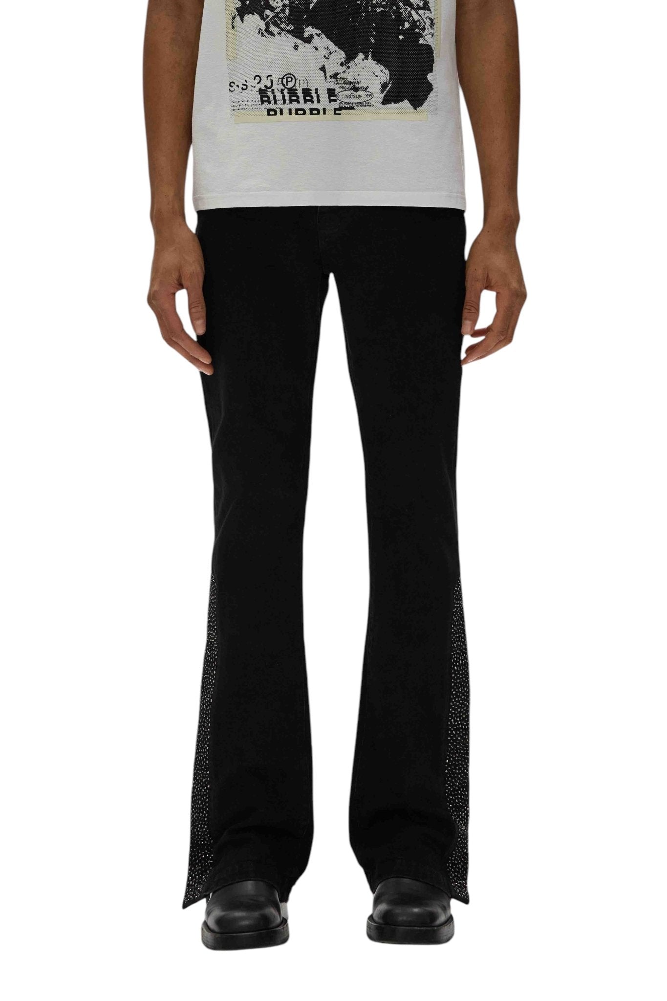 A person is wearing a white graphic T-shirt with PURPLE BRAND P067-FCNB Flare Crystal Side Snap Black pants and black shoes, paired with Purple Brand jeans.