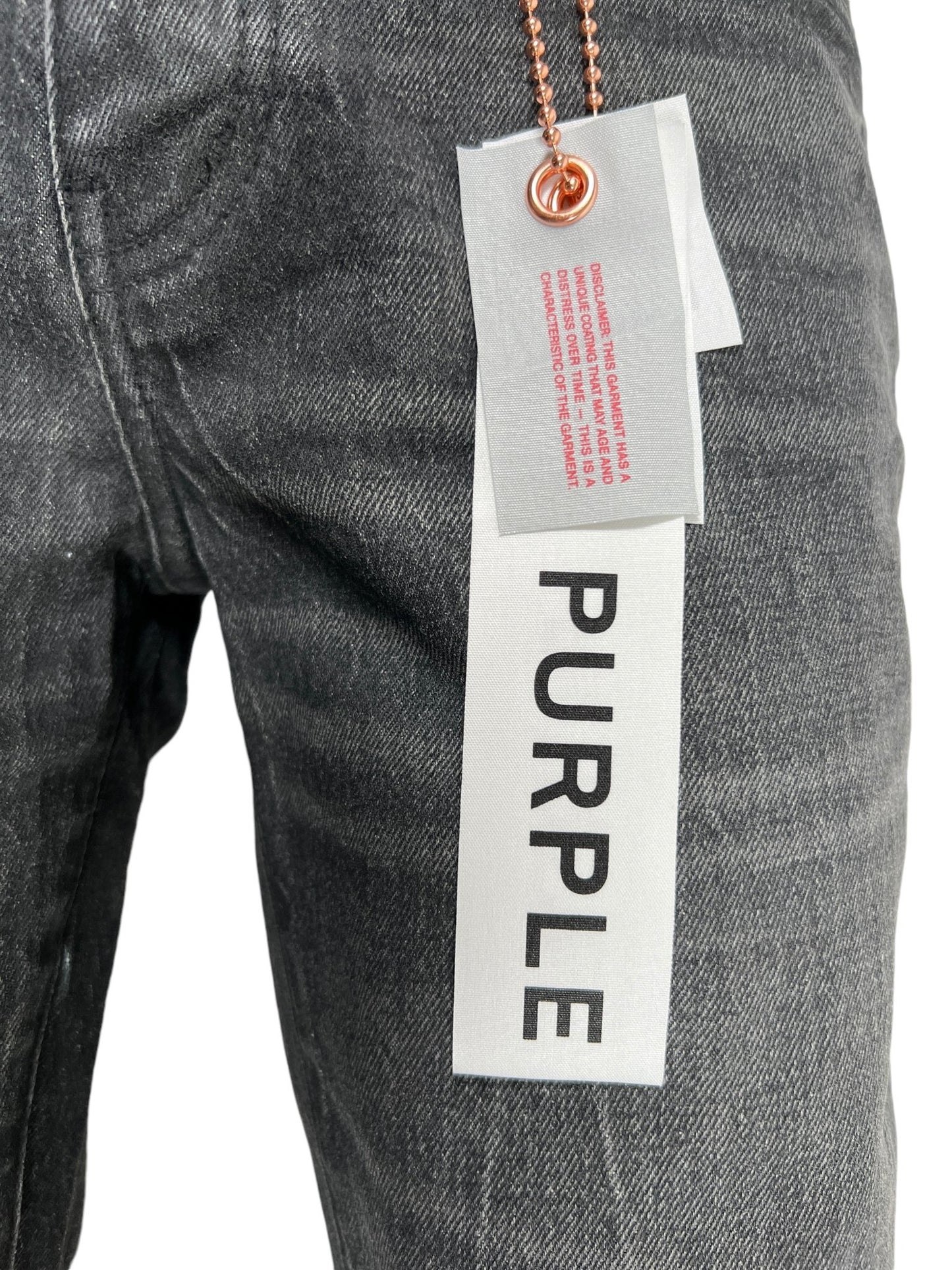 Close-up view of the PURPLE BRAND P072-SSVB SUPER STACK FLARE COATED BLACK jeans with a white tag featuring the words "PURPLE BRAND" in black letters and another tag with red text, both attached by a metal chain.