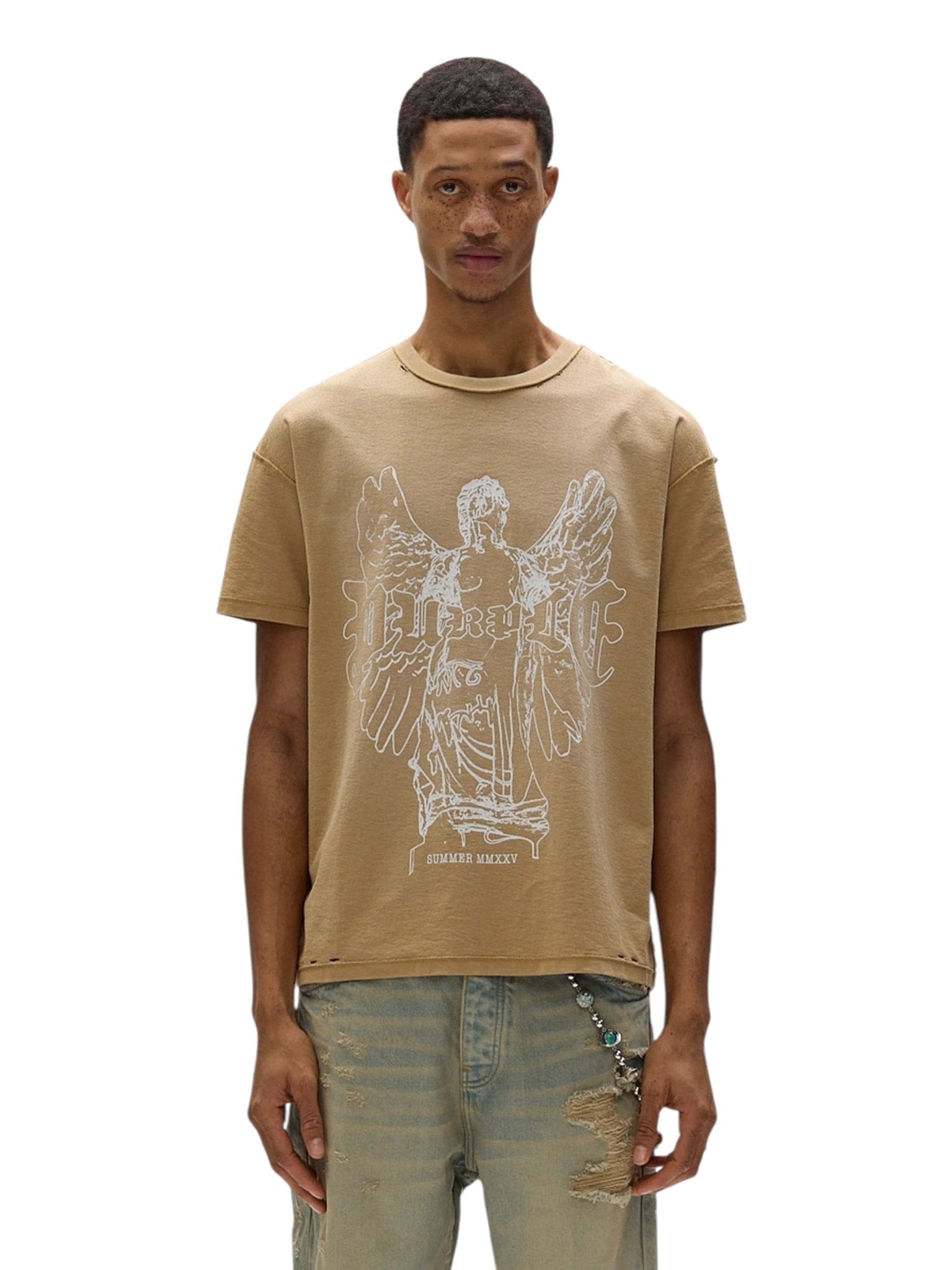 A person in a tan Purple Brand P101-JTGU Textured Inside Out Tee, made from 100% cotton and featuring an angel graphic with text, pairs it with distressed jeans against a plain white backdrop.