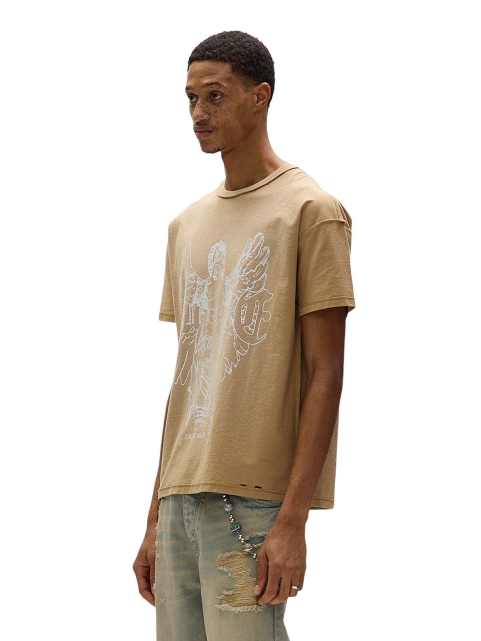 A person in a Purple Brand P101-JTGU Textured Inside Out Tee in tan, made from 100% cotton, pairs it with ripped jeans while standing against a white background.