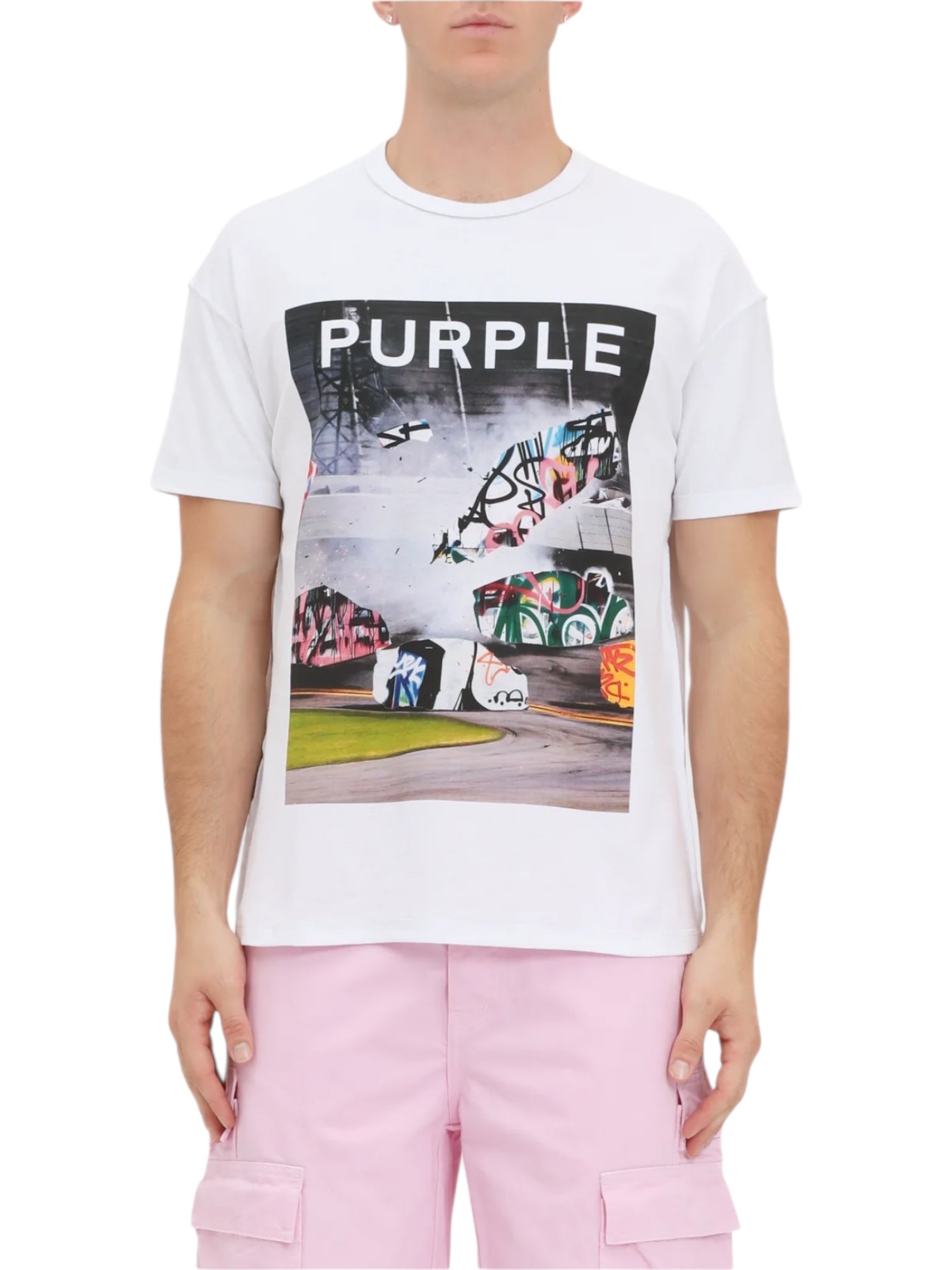 A person wears the PURPLE BRAND P101-TWPU325-Inside Out Tee in Brilliant White with "PURPLE" text, paired with light pink cargo shorts, and stands facing forward.