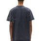 A person is shown from the back wearing a PURPLE BRAND P104-TBCS325-Textured SS Tee Black Beauty, featuring star-shaped stitched designs on the sleeves and upper back, paired with matching dark shorts.