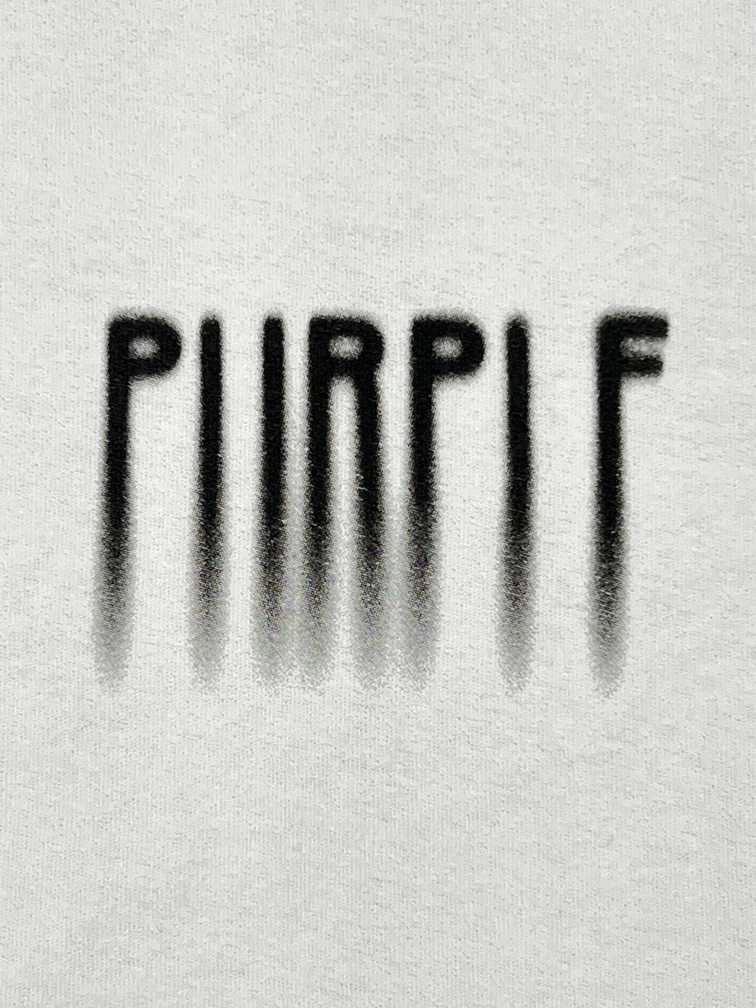 The PURPLE BRAND P104-TBWB Textured Jersey SS Tee White features "PURPLE" in black spray-painted letters with shadowing on a white 100% cotton T-shirt.