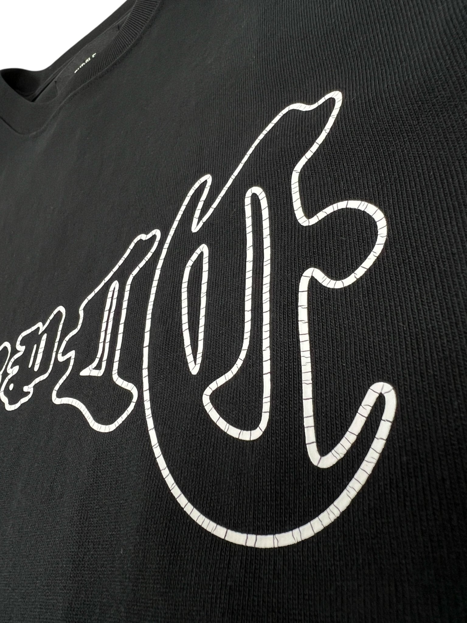 Close-up of the PURPLE BRAND Purple Brand P117-HBGO HWT Jersey SS Tee Black, featuring large white outlined stylized lettering on soft 100% cotton fabric.