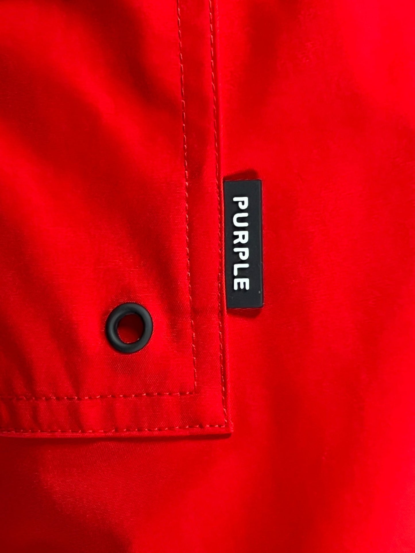 A close-up of lightweight red PURPLE BRAND P504-PRUC ALL ROUND SHORTS with a black tag labeled "purple.