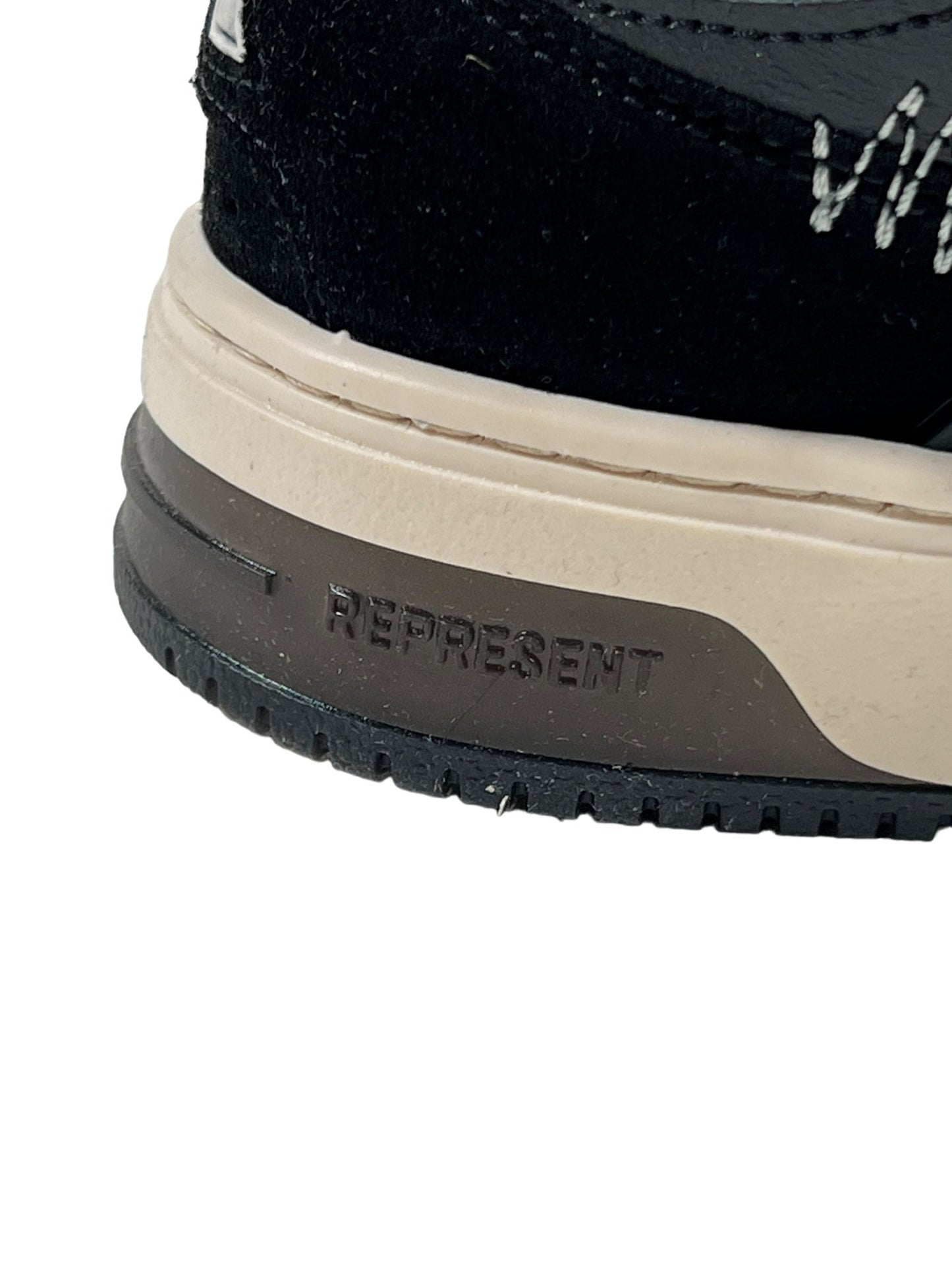 Sentence with replaced product and brand name: Close-up of a REPRESENT M12068-37 BULLY LEATHER BLACK sneaker with the word "represent" embossed on the beige sole, showing detailed stitching and retro skate-inspired tread.