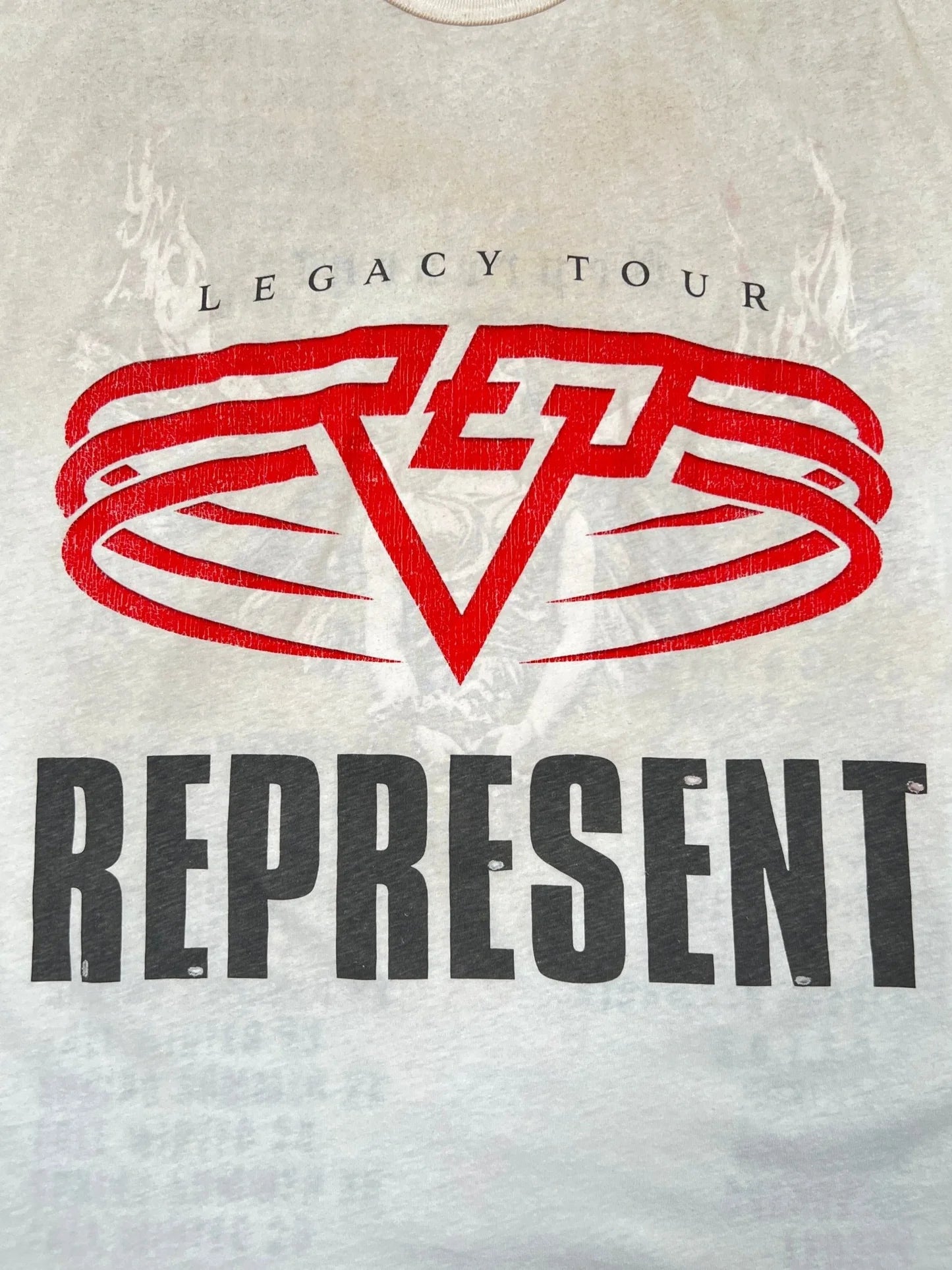 The REPRESENT MLM100176-30 Living Legacy T-shirt in washed ecru features "LEGACY TOUR" above a bold red abstract symbol and "REPRESENT" below, all crafted from soft organic cotton for comfort and style.