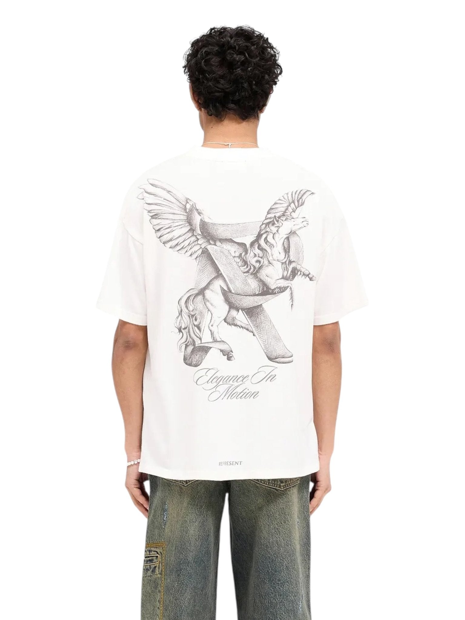 A person in a Represent MLM41066 Elegance in Motion Tee by REPRESENT, made of soft jersey cotton with an eagle and horse print on the back, paired effortlessly with loose jeans.