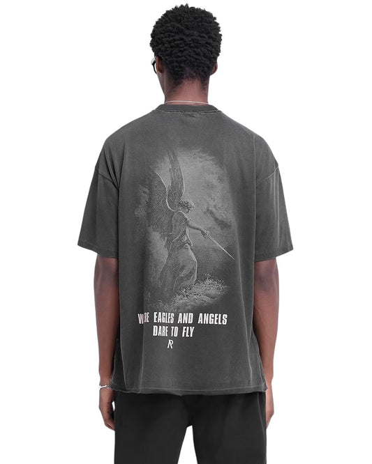 A person stands facing away, wearing the Represent MLM4222 Godspeed T-shirt in aged black with an oversized fit. The cracked graphic features an angel alongside the text "Where Eagles and Angels Dare to Fly.