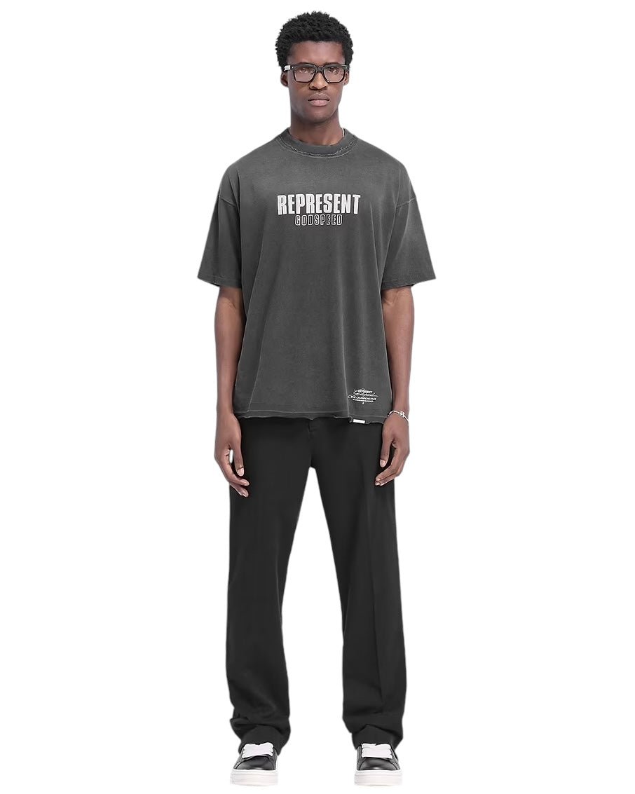 A person wearing a generously sized "Represent MLM4222 Godspeed T-shirt Aged Blk" with a distressed graphic, paired with black pants and sneakers, stands against a plain white background.