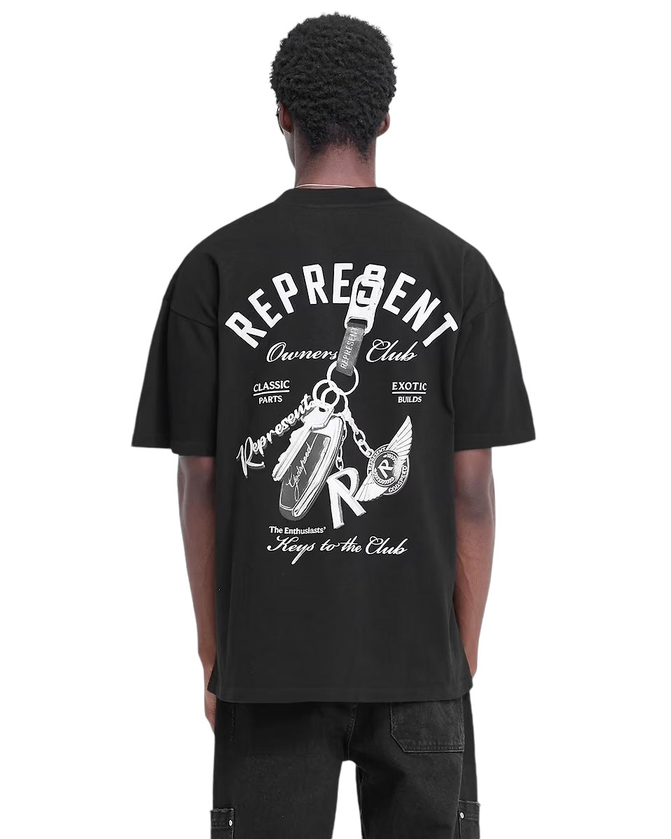 An individual is wearing the Represent MLM4236 Keys To The Club T-Shirt in Jet Black, designed by the brand REPRESENT. This oversized fit features a captivating pearl print graphic on the back, showcasing keys and text.