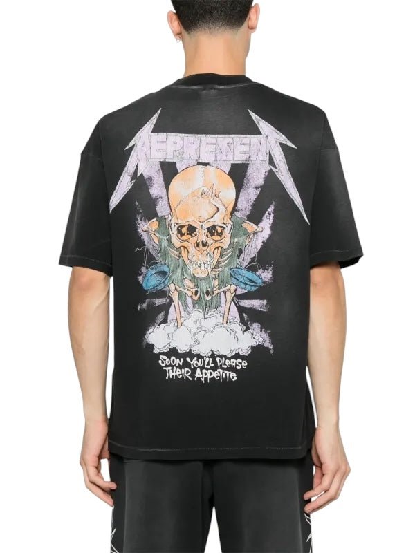 A fashion-forward individual wears the Represent MLM4352 Metallica Justice Tee in black by REPRESENT, showcasing a skull graphic and text: "REPRESENT" and "SOON YOU'LL PLEASE THEIR APPETITE," echoing an edgy Metallica Justice vibe.