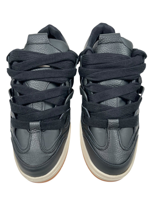 A pair of Represent MLM9599 Bully Black/Gum sneakers features a sleek leather upper and thick black laces, viewed from the top.