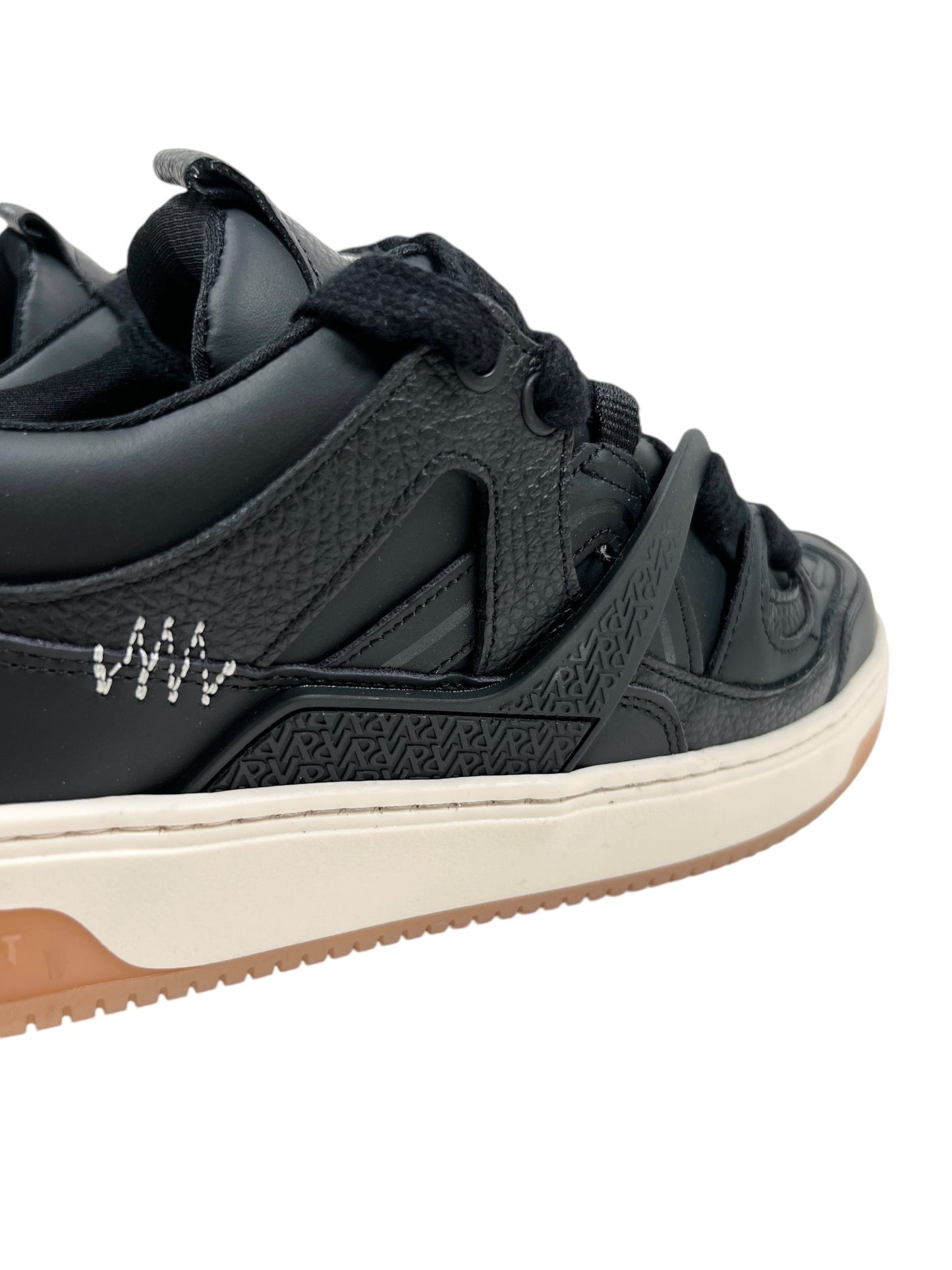 Close-up of the Represent MLM9599 BULLY BLACK/GUM sneaker featuring textured leather details and TPU overlays, paired with black laces and a white stitched pattern on the side. The off-white sole is accented with a gum-colored edge.