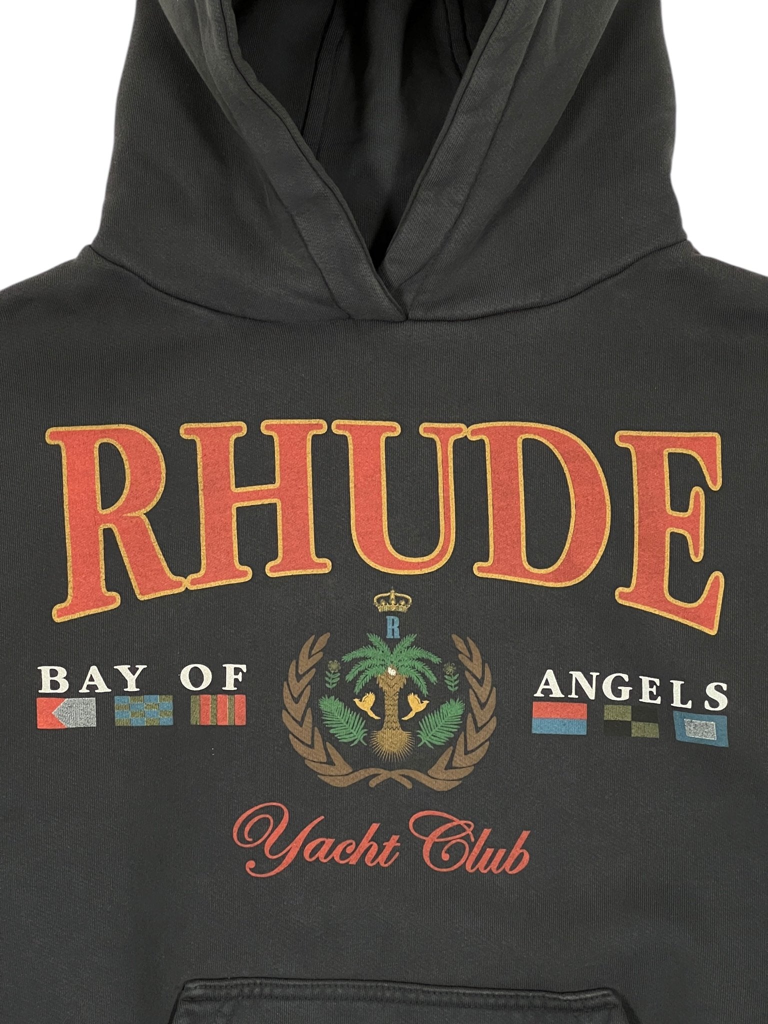 The Rhude Bay Of Angels Yacht Hood Black by RHUDE, made from 100% cotton, features 'RHUDE' and 'Bay of Angels' with nautical flags and 'Yacht Club' elegantly inscribed in red cursive.