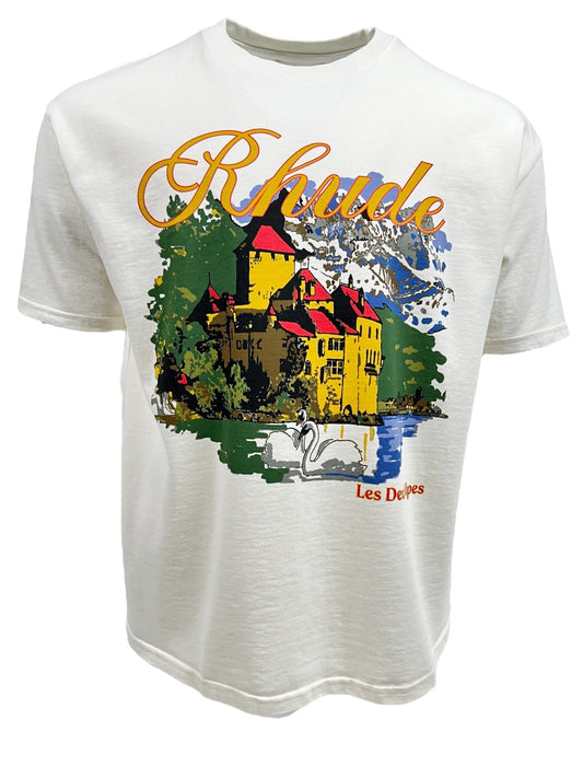 The RHUDE CHATAEU ALPES TEE VTG WHITE featuring a colorful illustration of a castle with the word "RHUDE" in large letters and "Les Délices" in smaller text beneath, along with swans on a lake in the foreground. This graphic t-shirt adds a touch of nostalgia to your casual wardrobe.