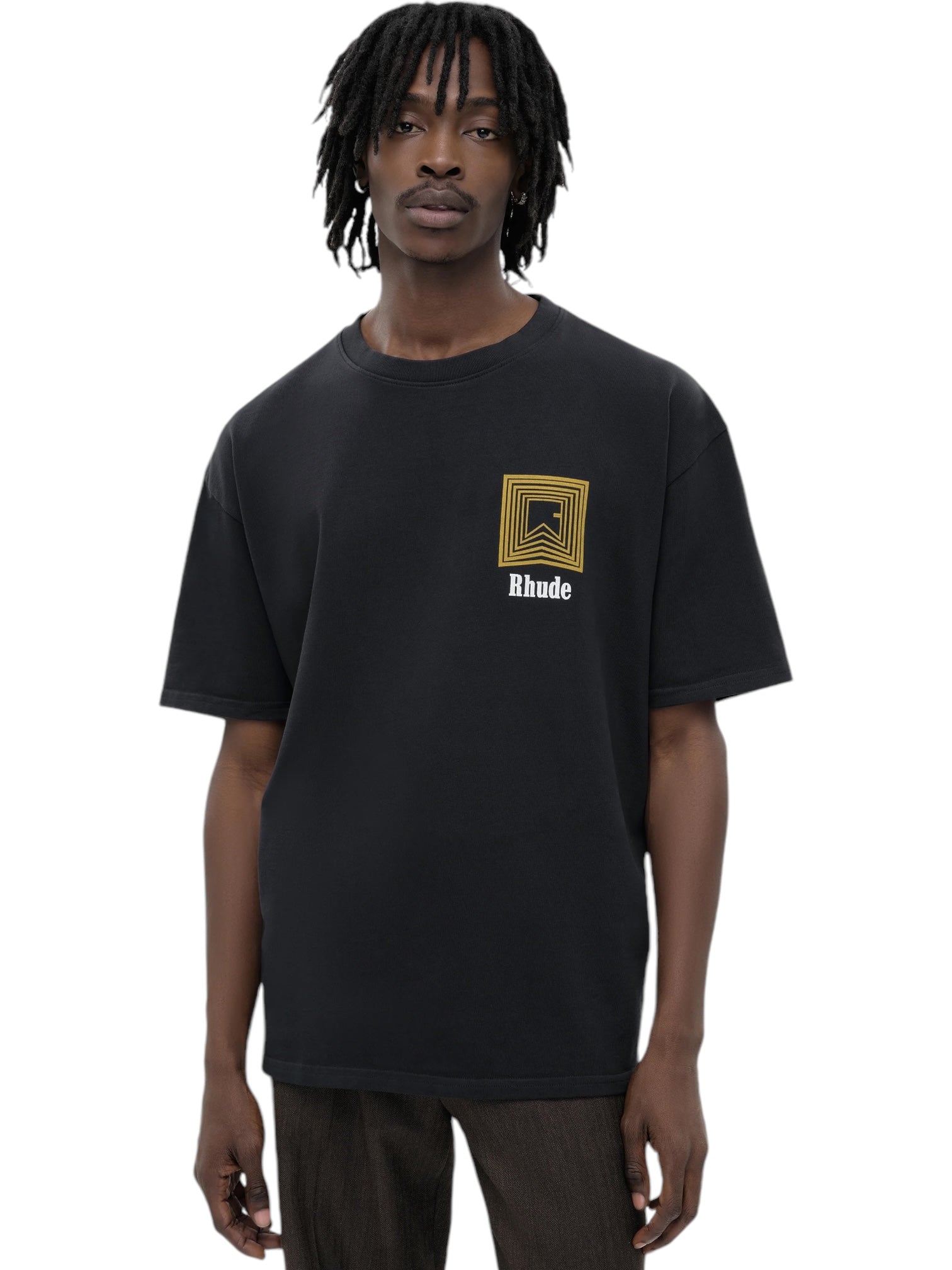 A person wearing a Rhude Chevron Logo Repeat Tee Vtg Black, featuring a design from RHUDE, stands against a plain background.