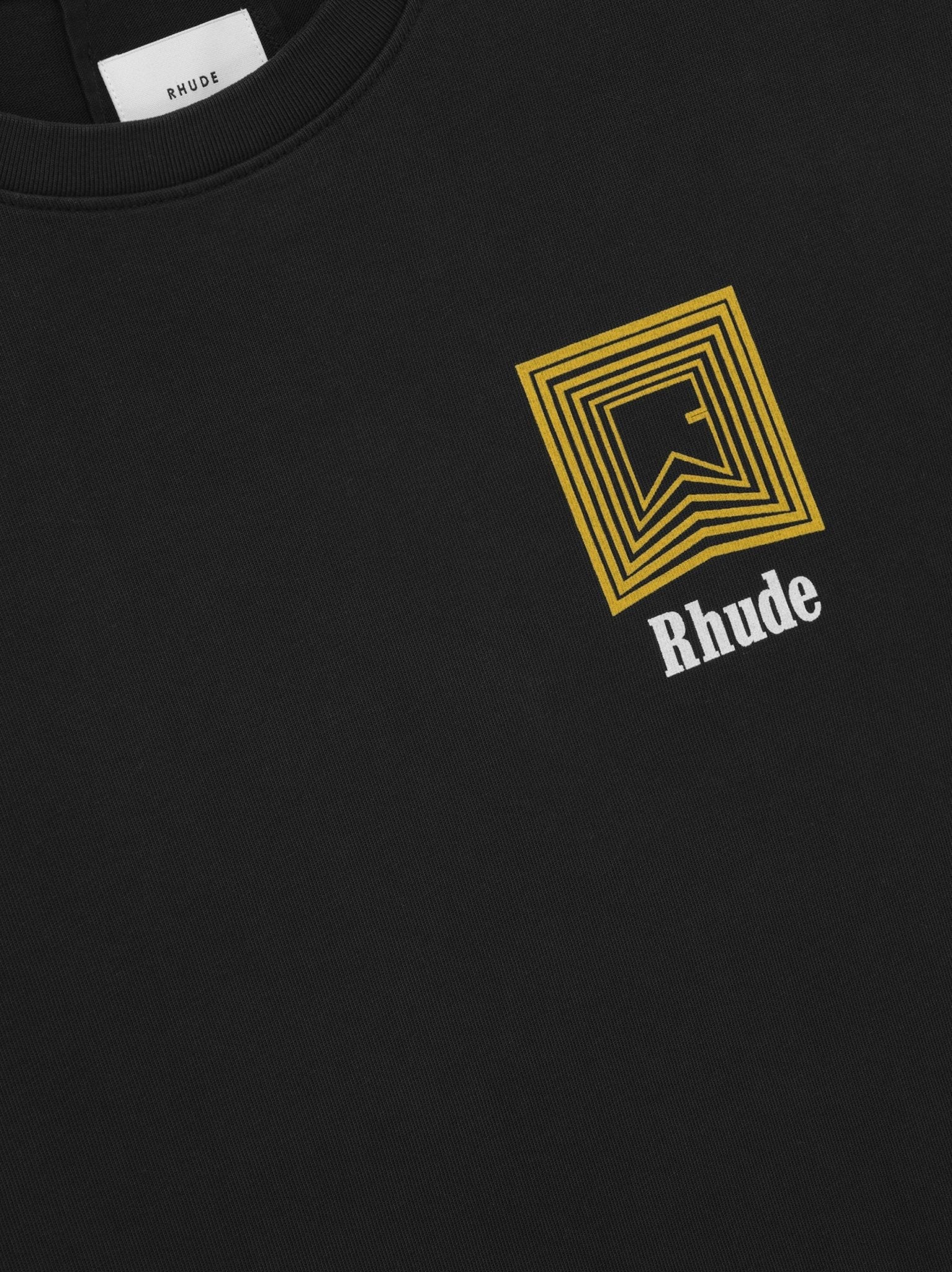 Rhude Chevron Logo Repeat Tee in vintage black by RHUDE features a custom-fit design with a yellow geometric pattern and the iconic white "Rhude" printed on the chest.