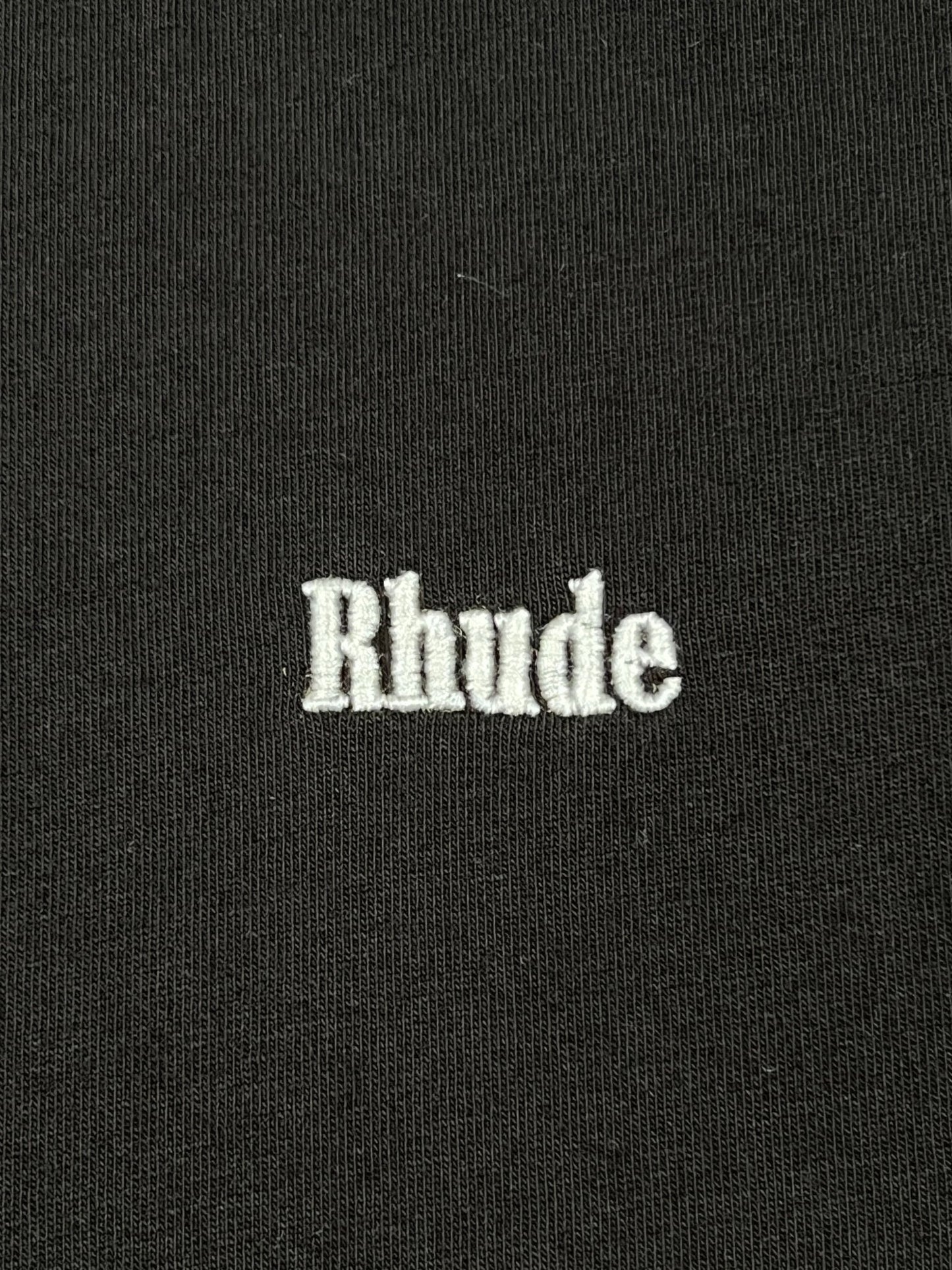 The Rhude Classique Reverse Ls Tee Black by RHUDE showcases "Rhude" beautifully embroidered in white on a black long sleeve shirt.